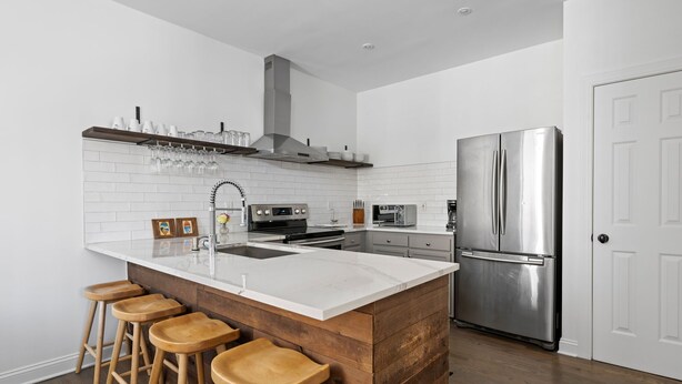 Una cocina moderna con una isla grande, electrodomésticos de acero inoxidable y taburetes de madera.