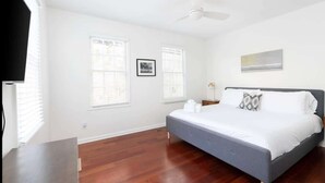 Ein Schlafzimmer mit Bett, Deckenventilator und zwei Fenstern mit Jalousien.