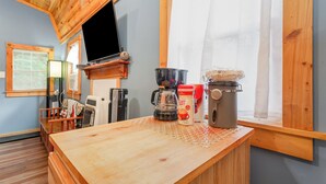 A wooden kitchen with a coffee maker, kettle, and a coffee machine on the counter. - Acorn Cottage | Adults-Only · Private Hot Tub · Secluded Hocking Hills Cabin (Logan)