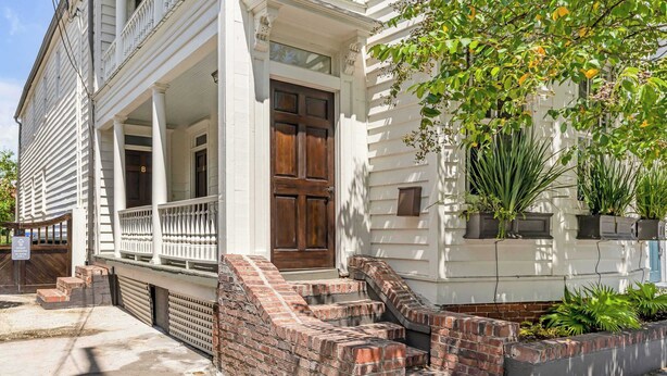 A two-story house with a front porch, brick steps, and a mailbox.