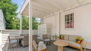 A covered outdoor patio with wicker furniture, a round table, and a sofa with cushions.