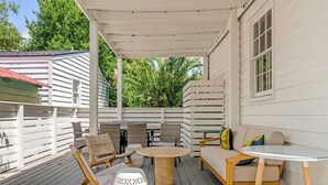 Un espace extérieur abrité, aménagé avec une table en bois, des chaises et un canapé.
