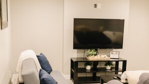 A modern living room with a grey sofa, a coffee table, and a flat-screen TV mounted on the wall. - COZY BASEMENT APARTMENT - PRIVATE ENTRANCE - NEAR PARK (SALT LAKE CITY)