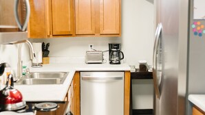 A modern kitchen with wooden cabinets, a stainless steel refrigerator, a dishwasher, and a coffee maker. - COZY BASEMENT APARTMENT - PRIVATE ENTRANCE - NEAR PARK (SALT LAKE CITY)