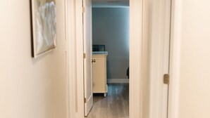 A hallway with a light wooden floor, white walls, and a framed picture on the left. - COZY BASEMENT APARTMENT - PRIVATE ENTRANCE - NEAR PARK (SALT LAKE CITY)
