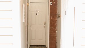 A hallway with a white door marked with a 'B' and a doormat that reads "Remove Your Shoes". - COZY BASEMENT APARTMENT - PRIVATE ENTRANCE - NEAR PARK (SALT LAKE CITY)