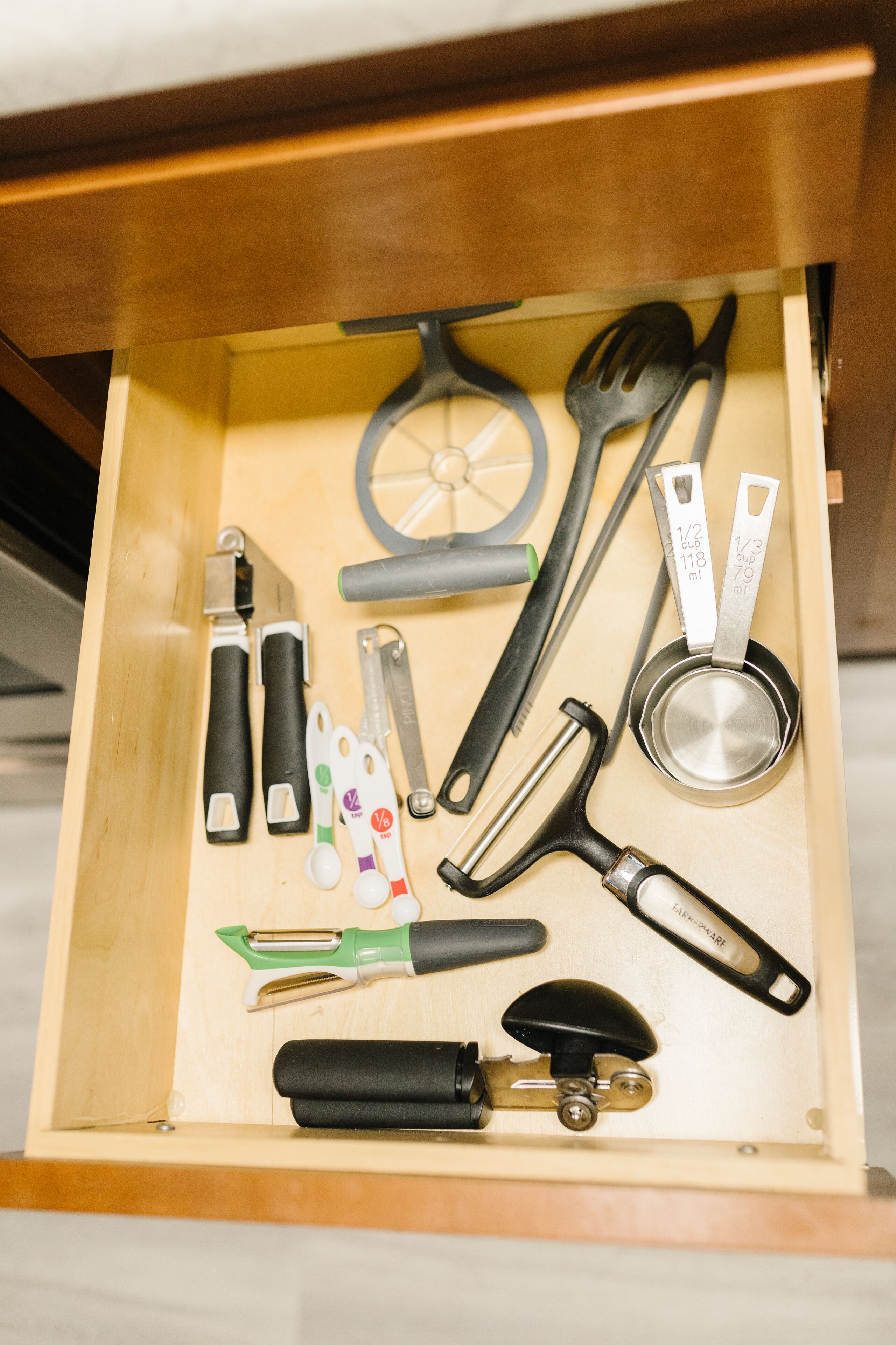 Un cajón con diversos utensilios y herramientas de cocina, como un rallador, espátula y tazas medidoras.