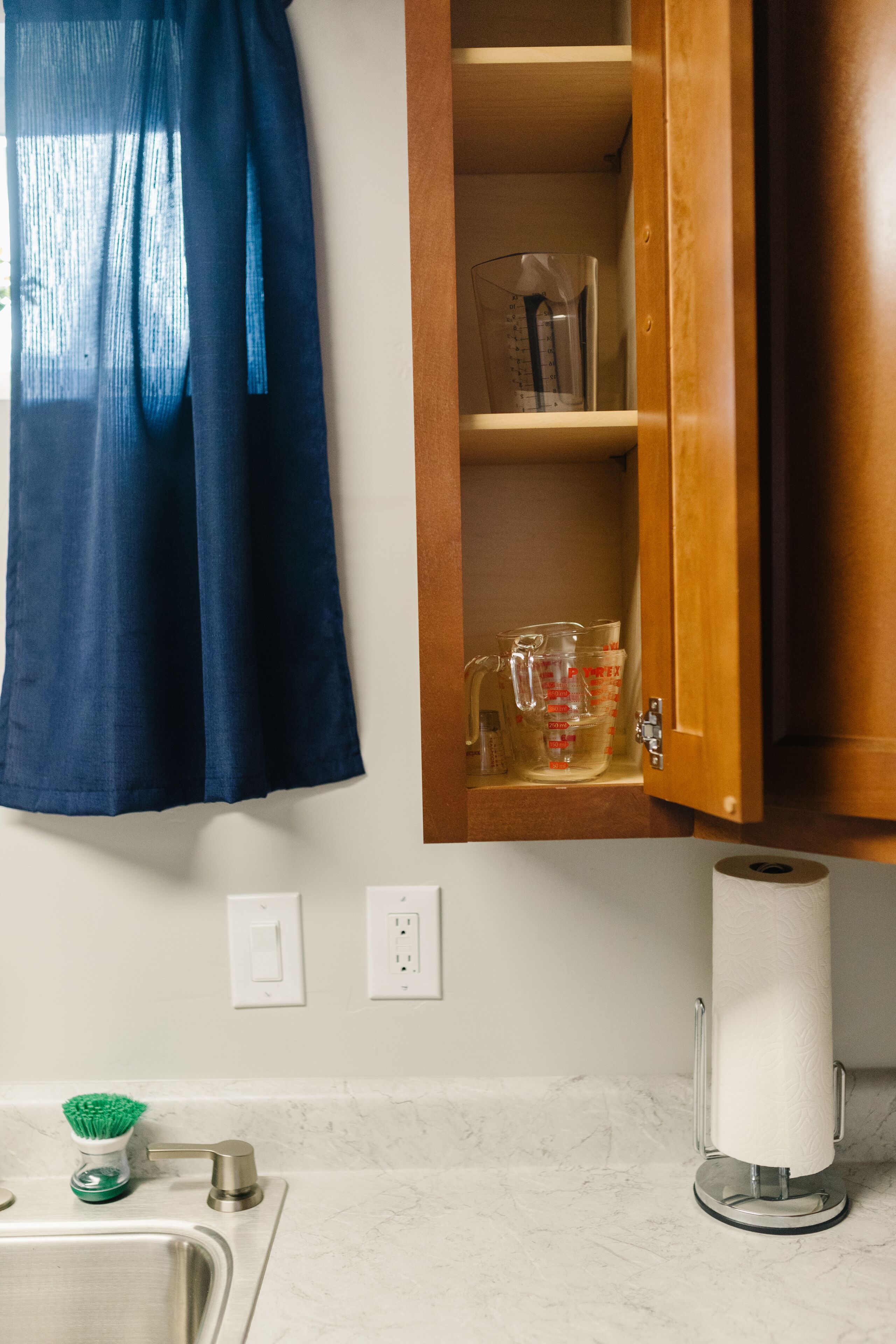 A bathroom with a sink, faucet, and a toilet paper holder.