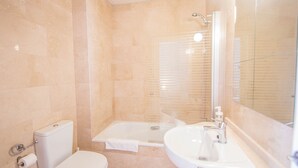 Un baño con inodoro, bañera y lavamanos.