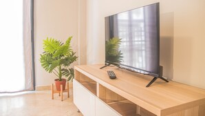 Un televisor de pantalla plana sobre un mueble de madera con un control remoto, una planta en maceta y un armario corredero.