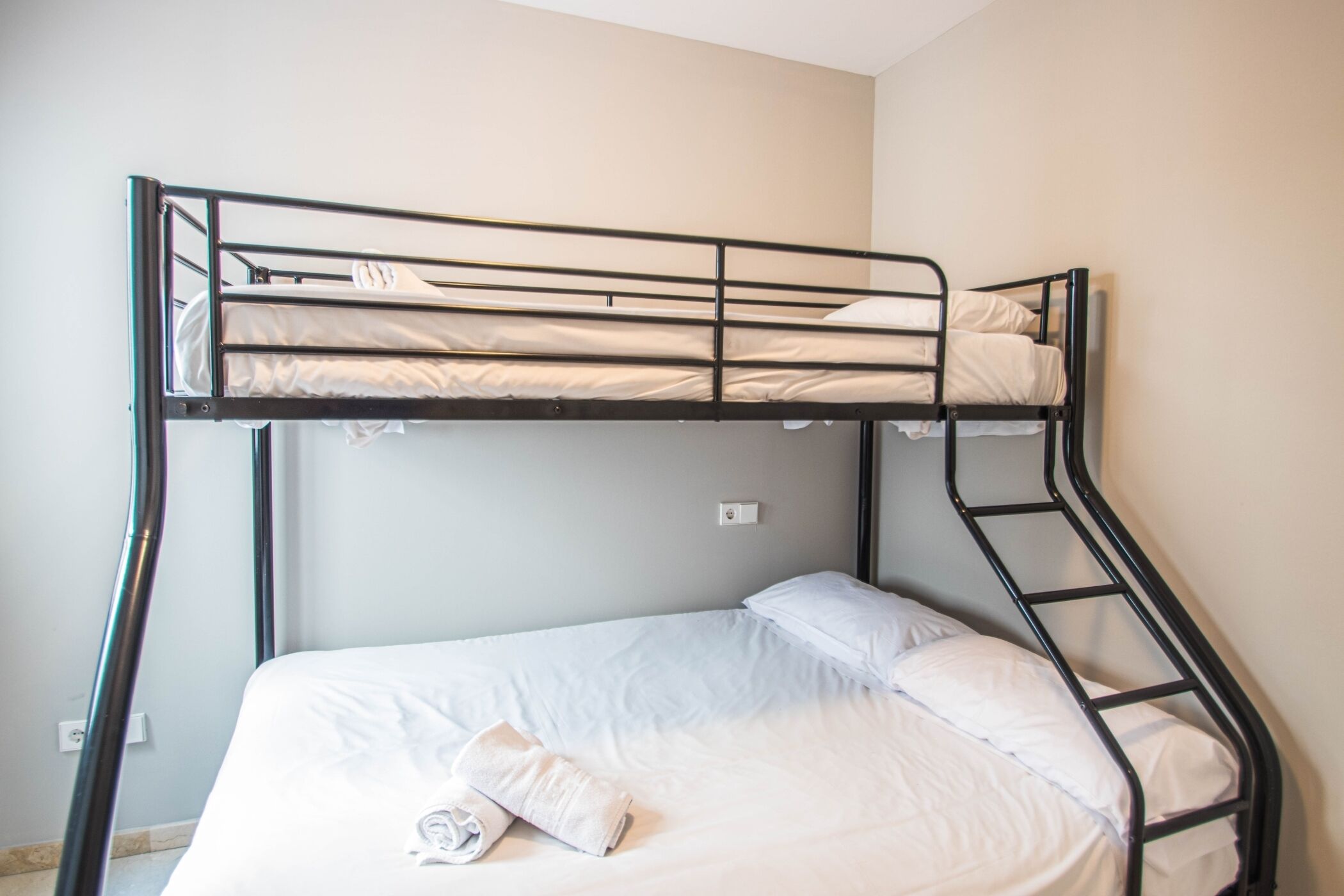A bunk bed with a ladder, white bedding, and a small towel on the lower bed.