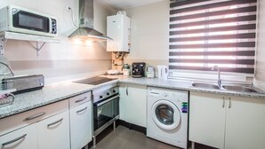 Eine kompakte Küche mit Mikrowelle, Backofen, Waschmaschine und integriertem Herd.