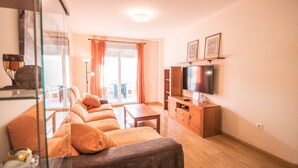 Ein Wohnzimmer mit einer Sofagarnitur, einem Fernseher und einem Holzschrank.