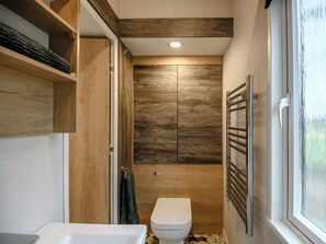 Ein kleines Badezimmer mit einer weißen Toilette, Holzschränken und einem Handtuchhalter.