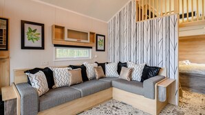 Ein modernes Wohnzimmer mit Ecksofa, großem Fenster und einer dekorativen Wandverkleidung.