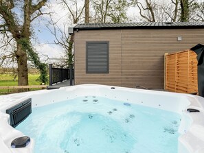 Ein Whirlpool mit einer Holzterrasse und einem Holzgebäude im Hintergrund.
