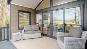 Ein überdachter Patio-Bereich mit Rattanmöbeln, großen Schiebegläsern und Blick ins Freie.