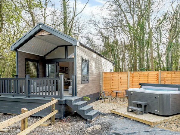 Eine kleine, moderne Blockhütte mit Veranda, Whirlpool und einer Holzterrasse.