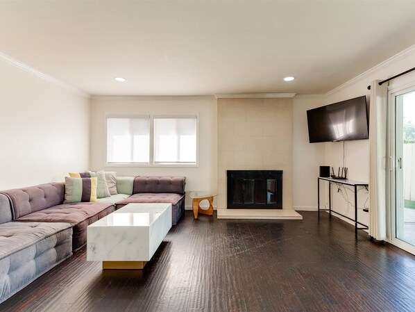 Una sala de estar moderna con un sofá modular, una mesa de centro blanca, una chimenea y un televisor montado en la pared.