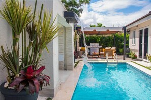 A swimming pool with a water feature, a barbecue area, and potted plants. - Modern Villa with private backyard pool (Drax hall)