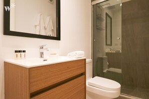 A modern bathroom with a white vanity, a glass shower enclosure, and a white toilet.