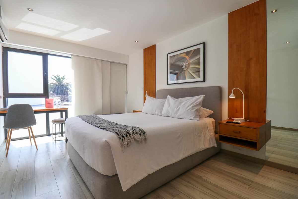 A modern bedroom with a large bed, a desk, and a chair.