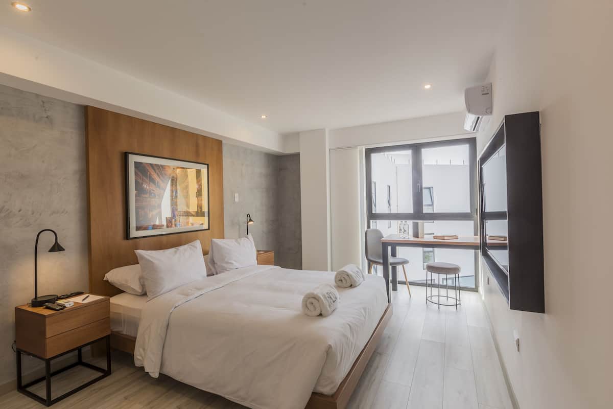 A modern bedroom with a large bed, a desk, and a chair.