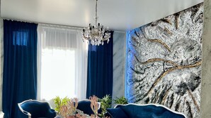Un soggiorno moderno con un divano blu scuro, un lampadario e un tavolo da pranzo.