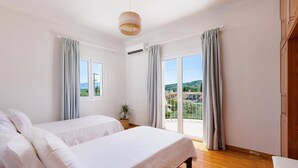 A bedroom with a bed, a potted plant, and a view through the window. - Villa Perla by Villa Plus (Kassiopi)