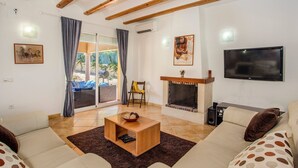 A living room with a fireplace, a TV, and a sofa. - Villa Magdalena Blanca by Villa Plus (Jávea)