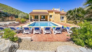 A poolside area with lounge chairs and a swimming pool, surrounded by greenery and a hillside. - Villa Magdalena Blanca by Villa Plus (Jávea)