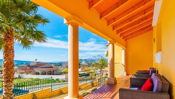 A covered outdoor area with a terrace, a view of a mountain, and a building in the background. - Villa Magdalena Blanca by Villa Plus (Jávea)