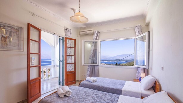Een slaapkamer met twee bedden, uitzicht op zee en een balkon.