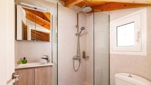 Ein modernes Badezimmer mit Glasdusche, Holzwaschtisch und Toilette.