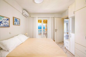 A bedroom with a bed, a wardrobe, and a balcony with a view.