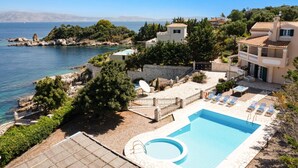 Ein Küstenhotel mit Swimmingpool, Liegestühlen und Meerblick.