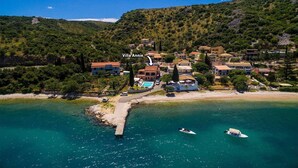 An aerial view of a coastal village with villas, a beach, and boats. - Villa Annie by Villa Plus (Imerolia)