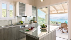 Eine moderne Küche mit einer Glasinsel, Edelstahlgeräten und Meerblick.