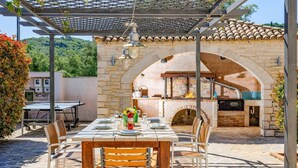 Un'area pranzo all'aperto con una pergola, un arco in pietra e un forno a mattoni.