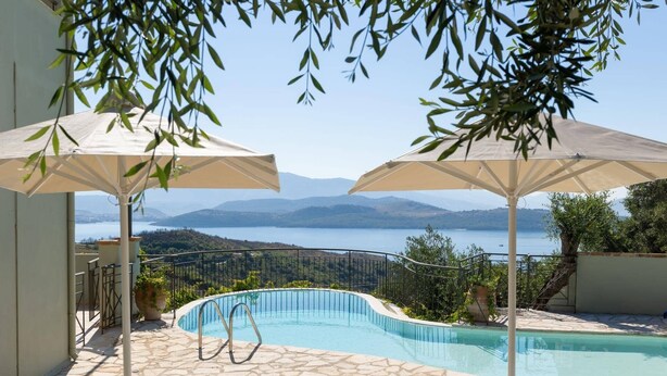 A pool area with lounge chairs and umbrellas, overlooking a lake and mountains. - Villa Firefly by Villa Plus (Άγιος Στέφανος)