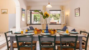 A dining area with a table set for four, surrounded by chairs with woven seats. - Villa Foula by Villa Plus (Άγιος Στέφανος)