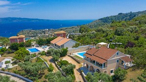 An aerial view of a coastal property with two villas, Villa Petra and Villa Ftelias, featuring Mediterranean architecture, a swimming pool, and lush greenery. - Villa Ftelias by Villa Plus (Άγιος Στέφανος)