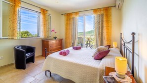 A bedroom with a bed, a desk, a dresser, and a balcony with a table and chairs. - Villa Gina by Villa Plus (Ionian Islands)
