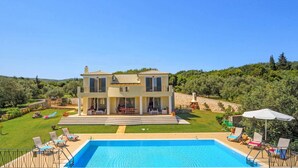 A two-story house with a swimming pool, outdoor seating, and a view of a green landscape. - Villa Gina by Villa Plus (Ionian Islands)