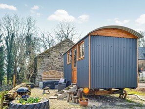 Une petite cabane rustique avec un mur en pierre et une terrasse en bois.