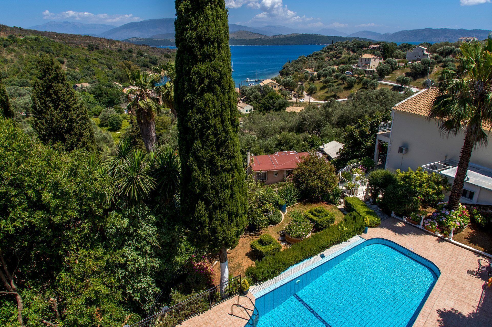 Área da piscina com vista para o mar e vegetação ao redor.