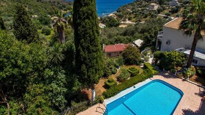 A pool area with a view of the sea and surrounding greenery. - Villa Kerkyra by Villa Plus (Άγιος Στέφανος)