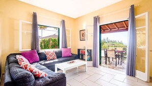 Ein Wohnzimmer mit Sofa, Couchtisch und Blick ins Freie.