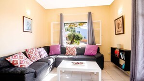 Ein Wohnzimmer mit grauem Sofa, weißem Couchtisch und Bücherregal.