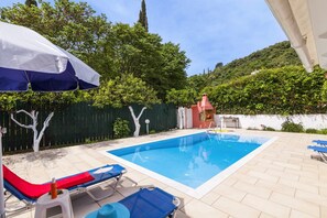 A swimming pool with lounge chairs and a barbecue area.